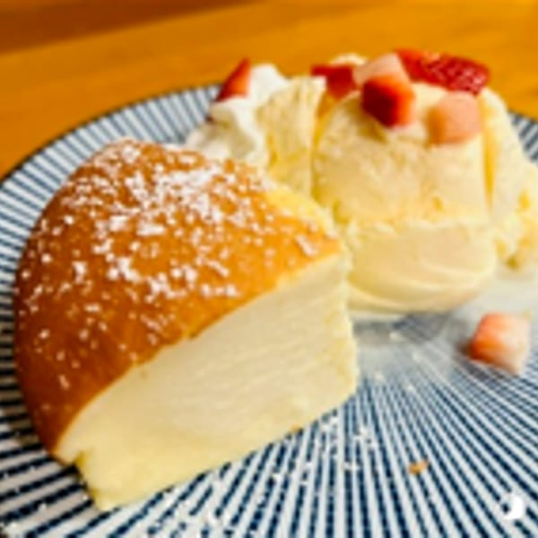 Fluffy Japanese cheesecake with powdered sugar, vanilla ice cream, whipped cream, and strawberries.