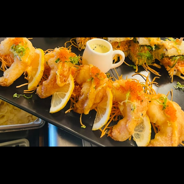 Golden fried shrimp with lemon slices, orange tobiko, and a side of creamy dipping sauce.