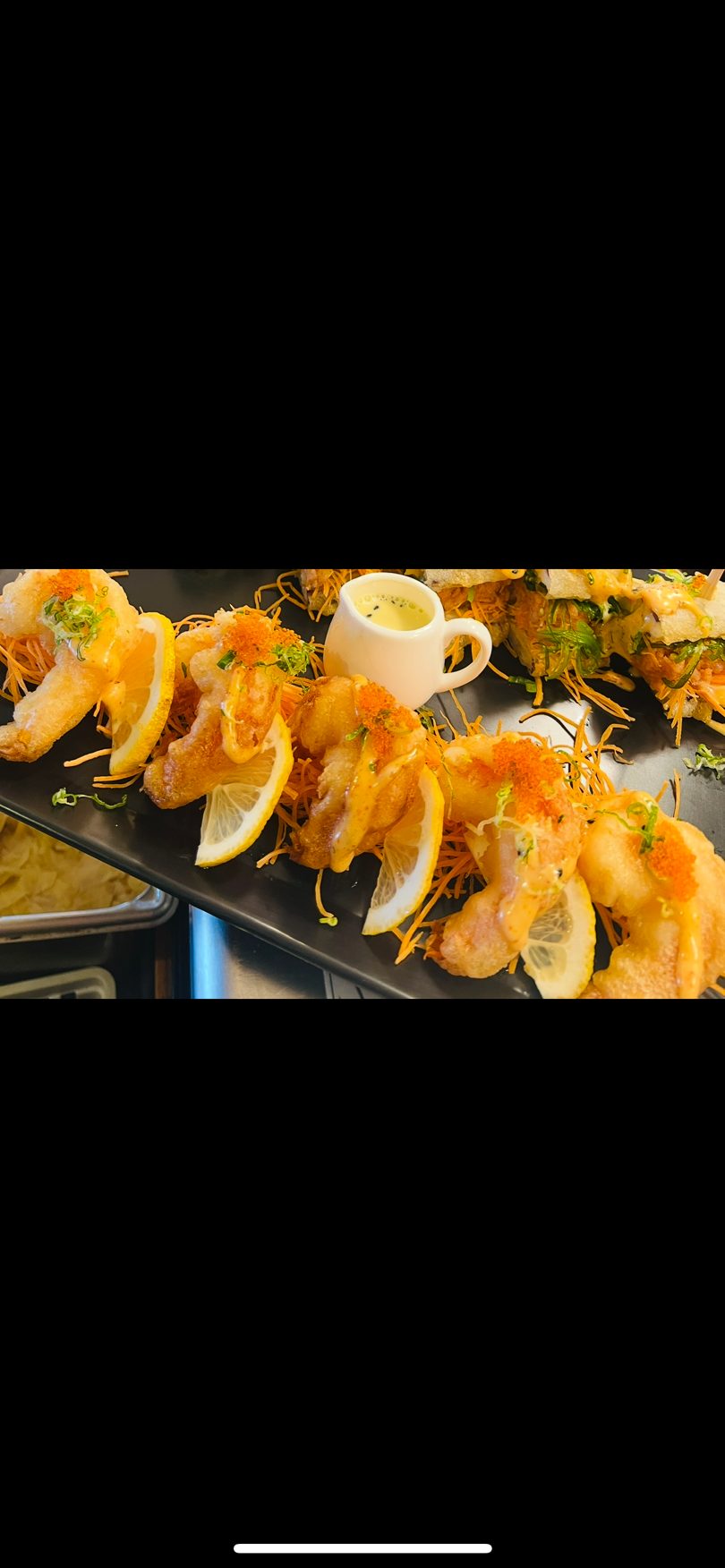 Golden fried shrimp with lemon slices, orange tobiko, and a side of creamy dipping sauce.