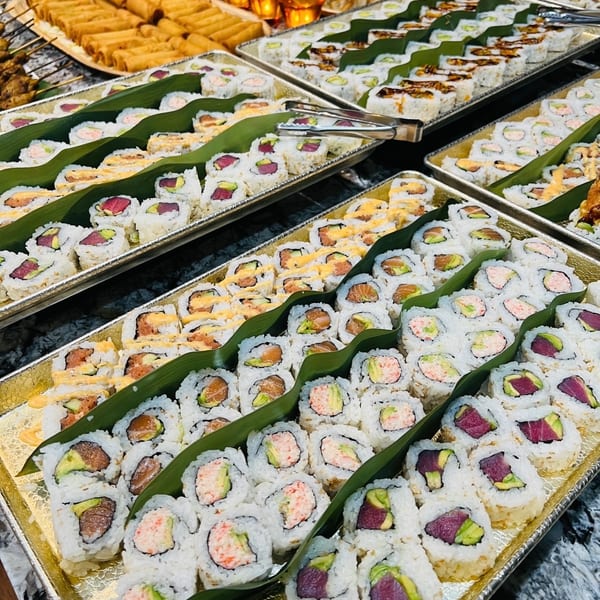 Assorted maki rolls on gold platters with spring rolls and skewers