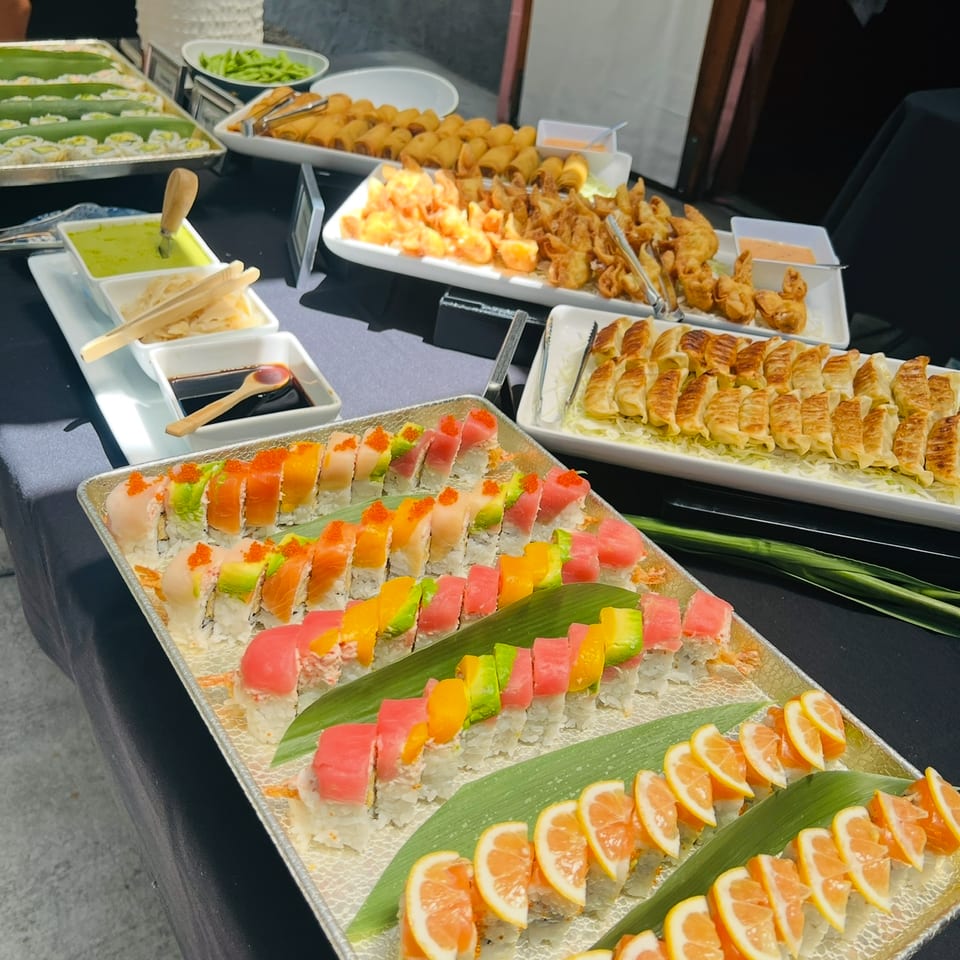 Catering buffet with specialty rolls, gyoza, spring rolls, and dumplings