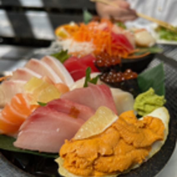 Close-up of a large platter of fresh sashimi, including uni, tuna, salmon, and yellowtail.