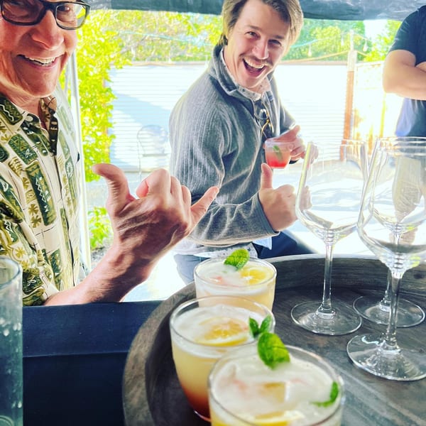Guests toasting with fresh cocktails on the bamboo-shaded patio