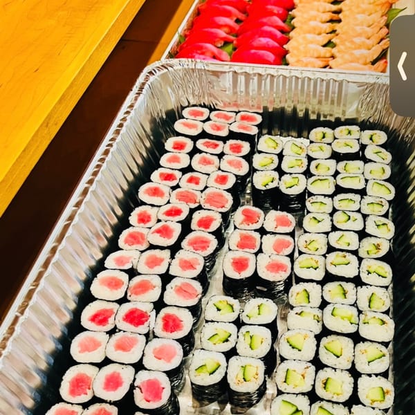 Large catering trays of tuna maki, cucumber rolls, and nigiri