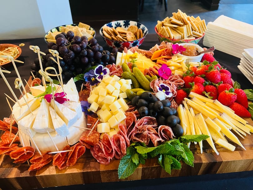 Charcuterie and cheese board with meats, cheeses, fruit, and olives