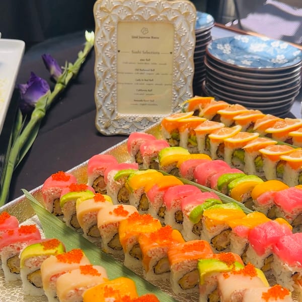 A vibrant buffet of assorted sushi rolls with various fish, avocado, and citrus toppings.