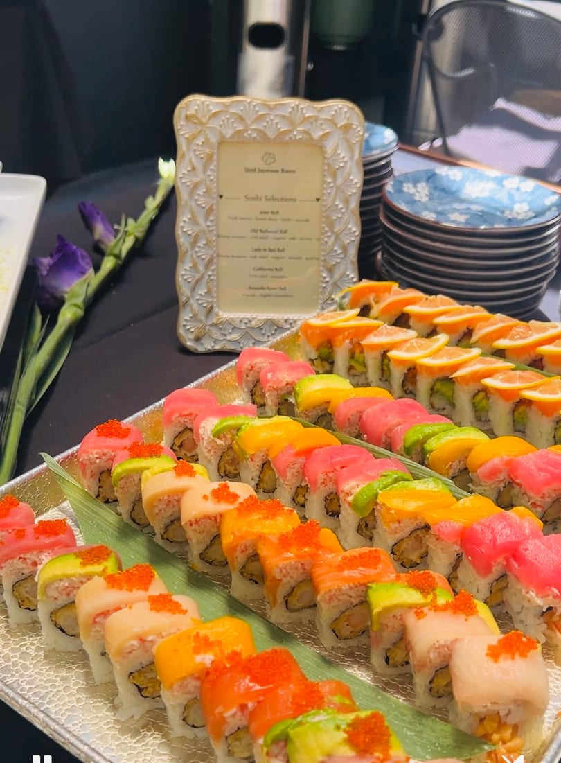 A vibrant buffet of assorted sushi rolls with various fish, avocado, and citrus toppings.