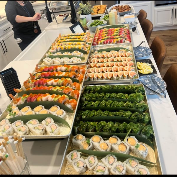 Full sushi catering spread with rainbow rolls, seaweed salad, and specialty rolls