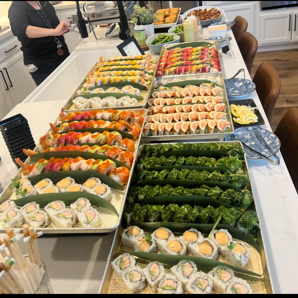 Full sushi catering spread with rainbow rolls, seaweed salad, and specialty rolls